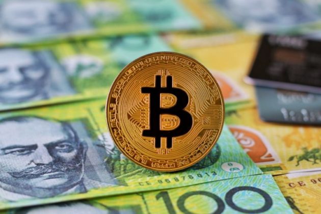 A physical illustration of Bitcoin is standing above Australian dollars (AUD)