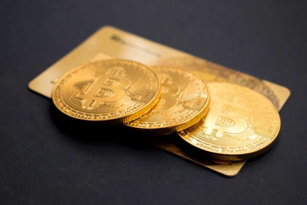 Bitcoin (BTC) is illustrated as physical gold coins above a gold card