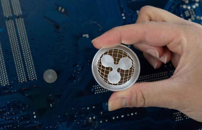 A person is holding a physical model of Ripple (XRP) token