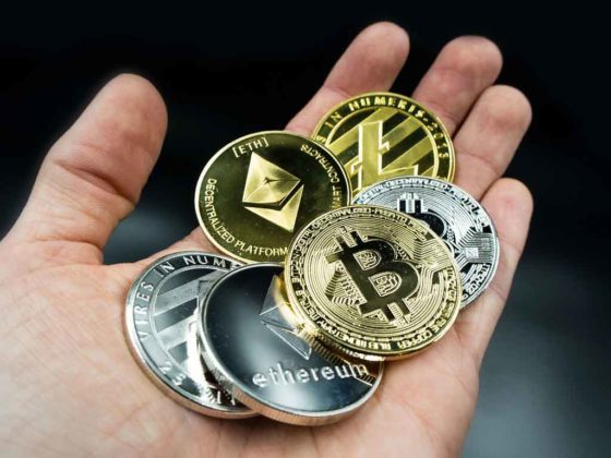 Cryptocurrencies are illustrated as physical coins in someone's hand